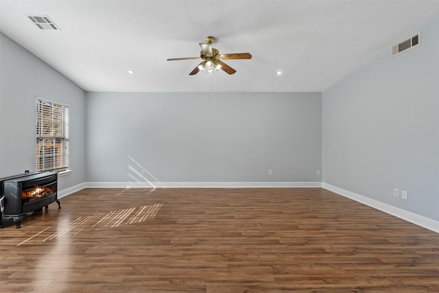 interior space with ceiling fan, a wood stove, and dark hardwood / wood-style floors