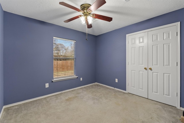 unfurnished bedroom with ceiling fan, light carpet, a closet, and a textured ceiling