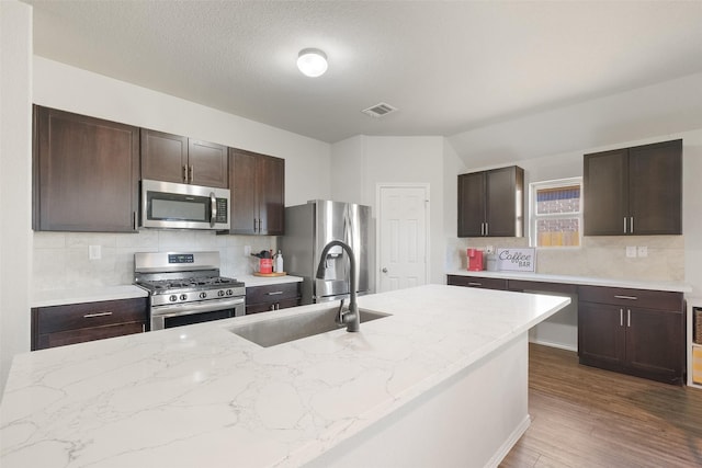 kitchen with lofted ceiling, dark hardwood / wood-style flooring, stainless steel appliances, sink, and backsplash