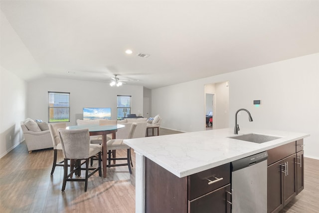 kitchen with lofted ceiling, stainless steel dishwasher, sink, light hardwood / wood-style flooring, and a kitchen island with sink