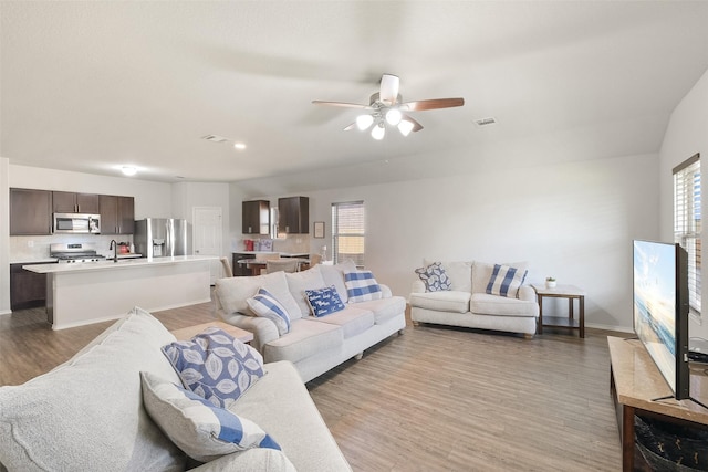 living room featuring ceiling fan, light wood-type flooring, and sink