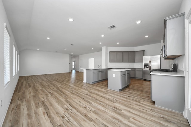 kitchen featuring visible vents, a kitchen island, open floor plan, stainless steel appliances, and gray cabinets