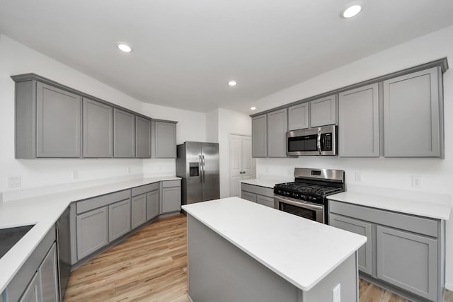 kitchen featuring recessed lighting, light wood-style floors, appliances with stainless steel finishes, gray cabinets, and a center island