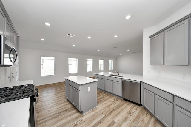 kitchen with open floor plan, gray cabinets, stainless steel appliances, light wood-type flooring, and recessed lighting