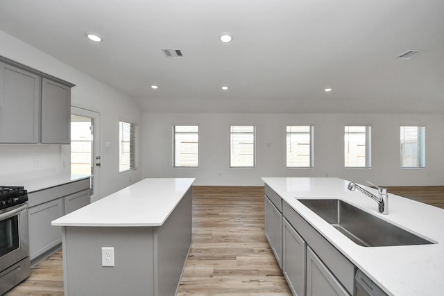 kitchen featuring stainless steel appliances, gray cabinets, visible vents, open floor plan, and a sink