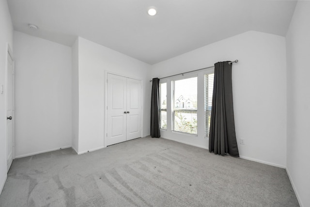 unfurnished bedroom featuring vaulted ceiling, carpet floors, a closet, and baseboards