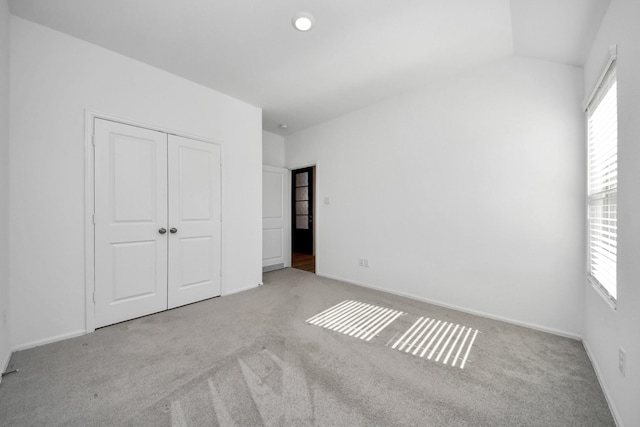 unfurnished bedroom featuring carpet floors, multiple windows, and a closet