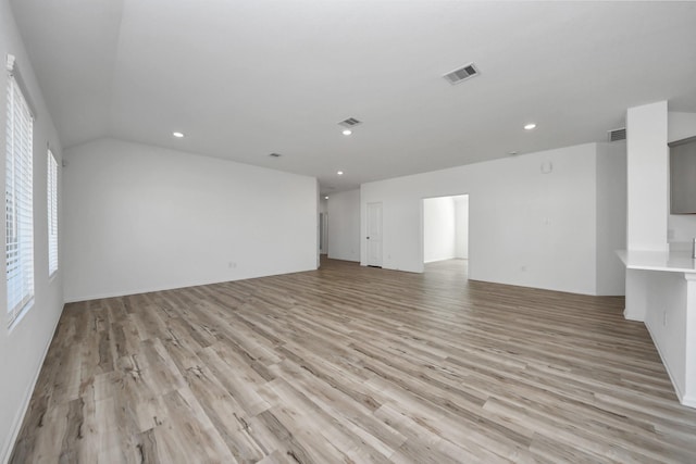 spare room featuring light wood-style floors, recessed lighting, visible vents, and vaulted ceiling