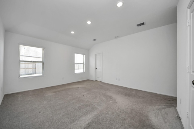 carpeted empty room featuring recessed lighting, visible vents, and vaulted ceiling