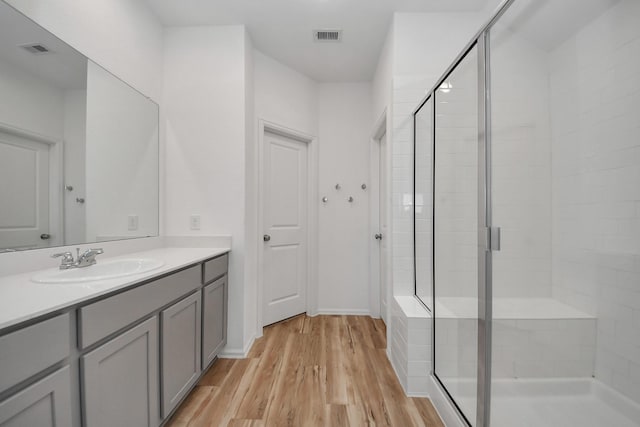 full bathroom featuring wood finished floors, a shower stall, and visible vents