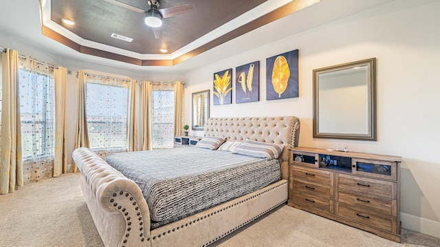 carpeted bedroom featuring ceiling fan and a raised ceiling