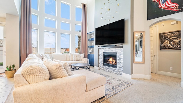 living room with light colored carpet, a wealth of natural light, a fireplace, and a high ceiling