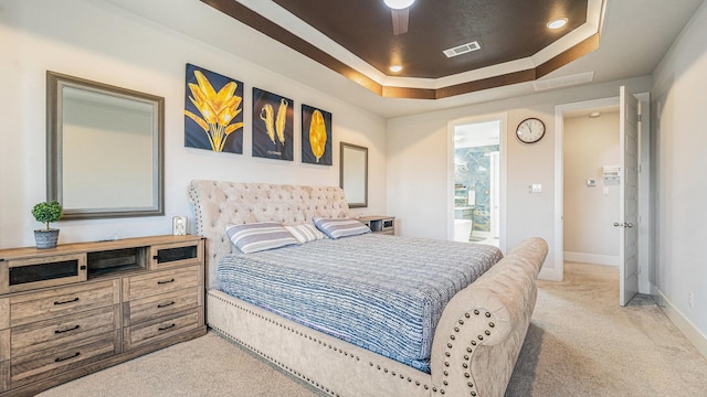 bedroom featuring ceiling fan, a tray ceiling, and light carpet