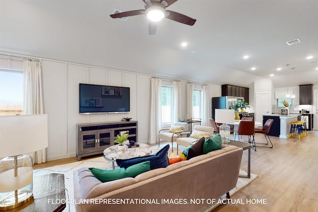 living room with light wood-style floors, lofted ceiling, visible vents, and recessed lighting