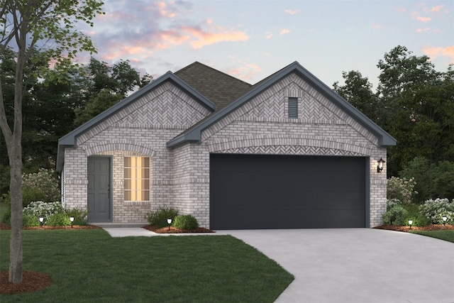 french country style house featuring a garage, a lawn, concrete driveway, roof with shingles, and brick siding