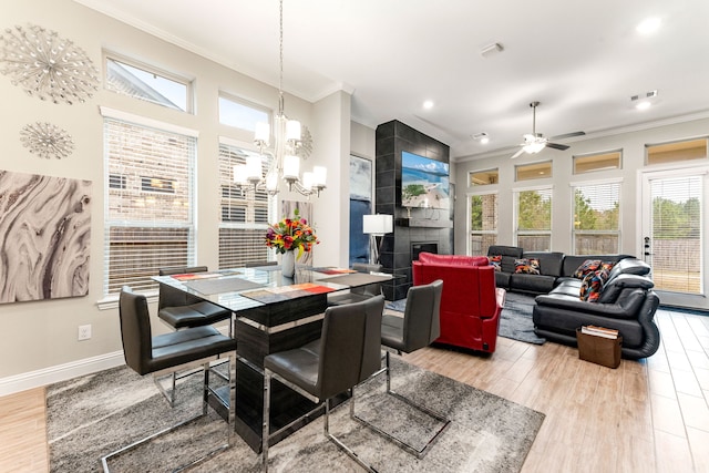 dining area featuring light wood-type flooring, a healthy amount of sunlight, and a tiled fireplace