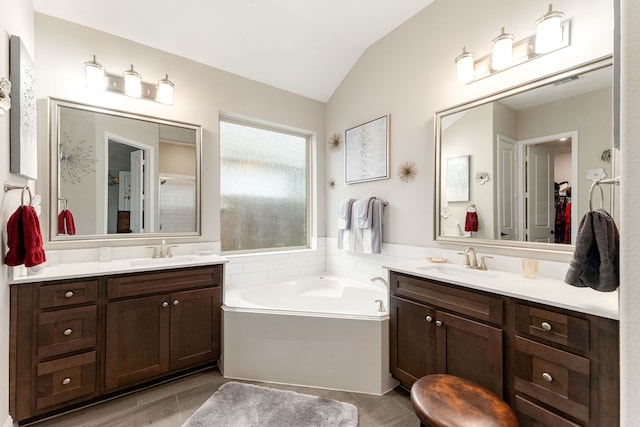 bathroom with lofted ceiling, vanity, and a tub to relax in