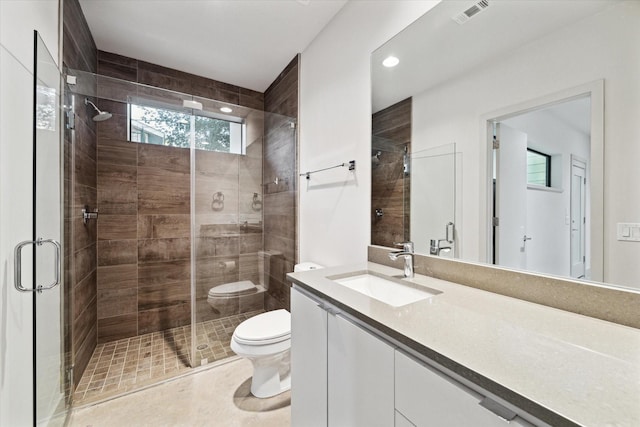 bathroom featuring a shower with shower door, a wealth of natural light, toilet, and vanity