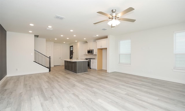 unfurnished living room with ceiling fan, sink, and light hardwood / wood-style flooring