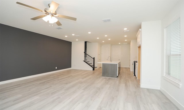 interior space with ceiling fan, sink, and light hardwood / wood-style floors