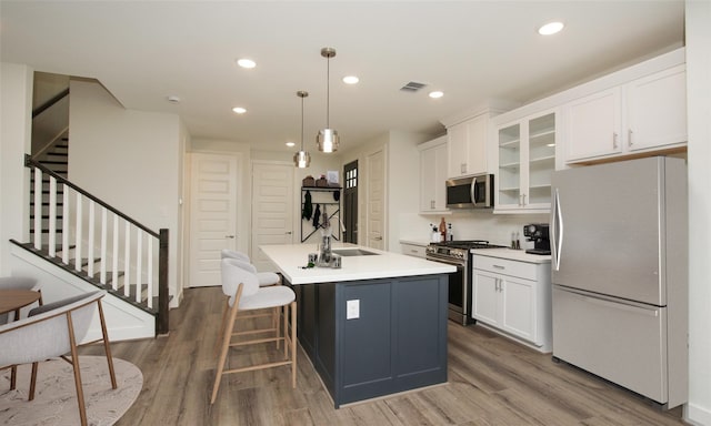 kitchen with pendant lighting, sink, appliances with stainless steel finishes, an island with sink, and dark hardwood / wood-style flooring