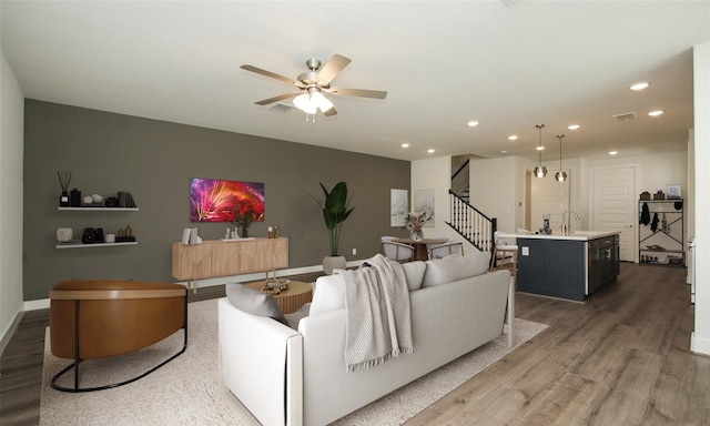 living room featuring sink, dark wood-type flooring, and ceiling fan