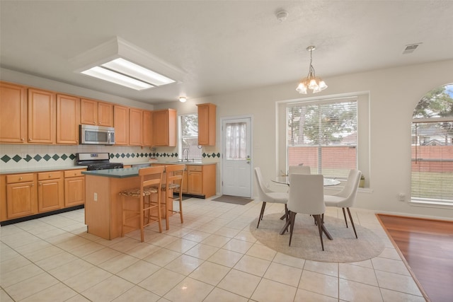 kitchen featuring hanging light fixtures, sink, a kitchen island, backsplash, and stainless steel appliances