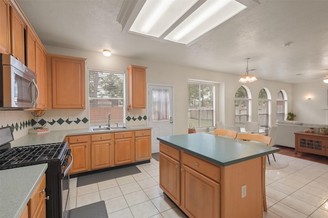 kitchen featuring sink, backsplash, a healthy amount of sunlight, a center island, and stainless steel appliances