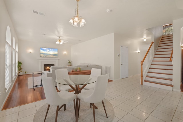 dining room with ceiling fan with notable chandelier and light tile patterned floors