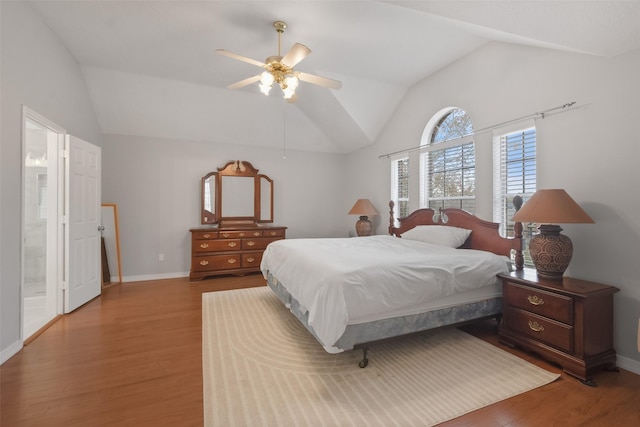 bedroom featuring ceiling fan, wood-type flooring, lofted ceiling, and ensuite bath