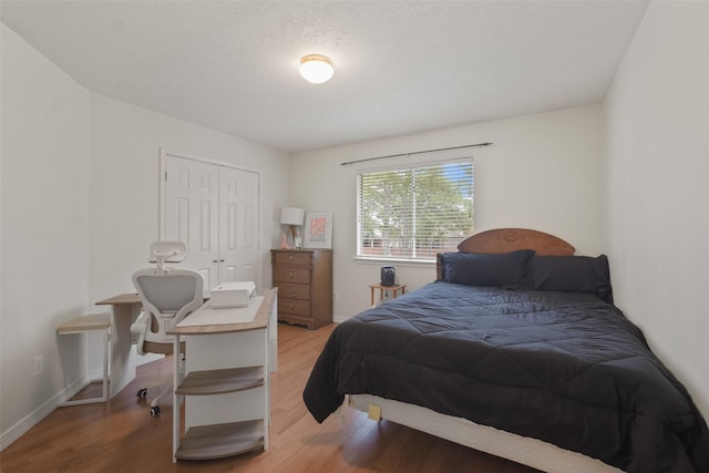 bedroom with a textured ceiling, light hardwood / wood-style flooring, and a closet