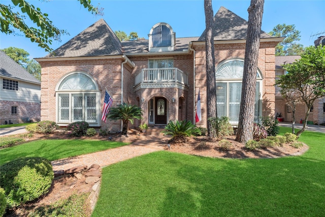 view of front of property featuring a front lawn and a balcony