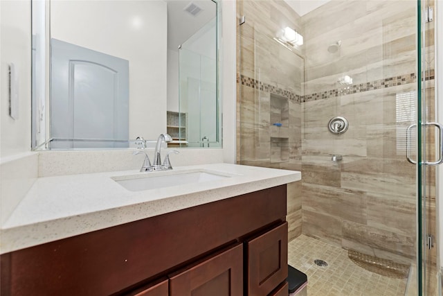 bathroom featuring a shower with shower door and vanity