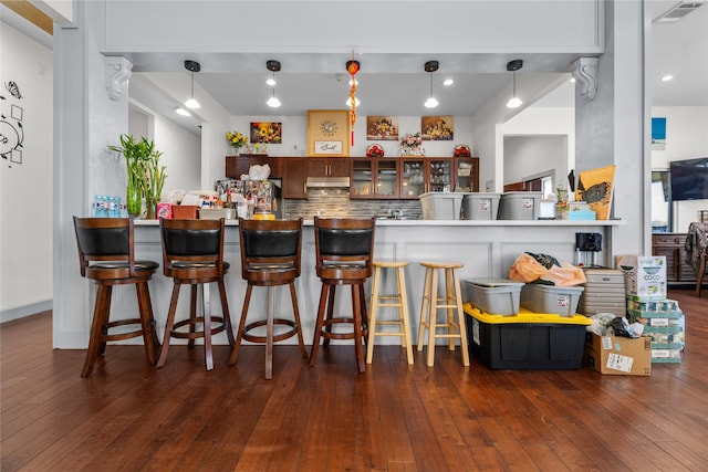 bar with decorative light fixtures, backsplash, dark wood-type flooring, and stainless steel refrigerator