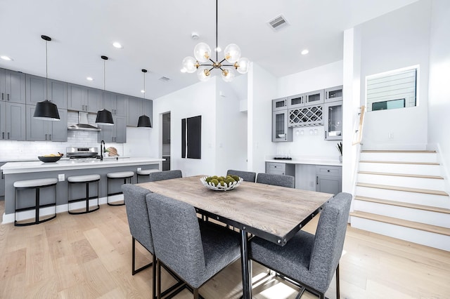 dining space featuring a chandelier, light hardwood / wood-style flooring, and indoor wet bar