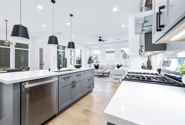 kitchen with hanging light fixtures, sink, an island with sink, light hardwood / wood-style floors, and stainless steel appliances