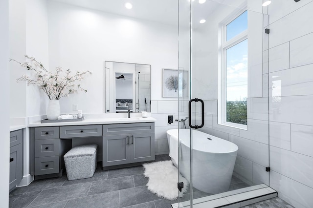 bathroom featuring shower with separate bathtub, vanity, and tile walls