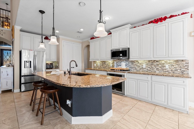 kitchen featuring sink, a center island with sink, backsplash, stainless steel appliances, and white cabinets