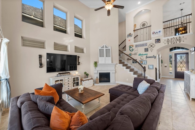 living room featuring a towering ceiling, light tile patterned floors, and ceiling fan