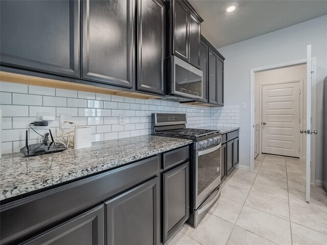 kitchen with tasteful backsplash, light tile patterned floors, stainless steel appliances, and light stone countertops