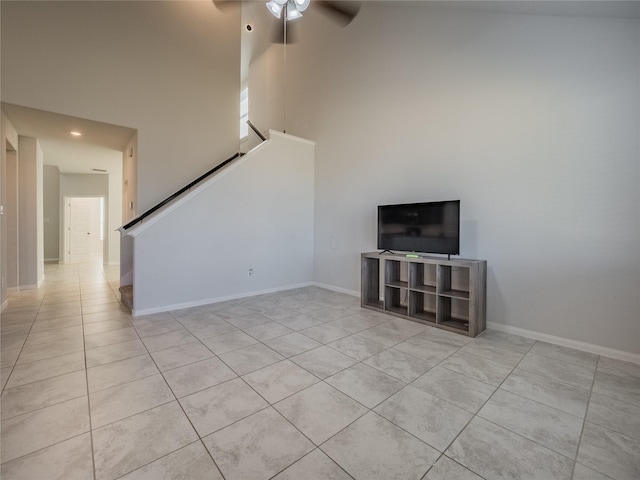 unfurnished living room featuring ceiling fan, a high ceiling, and light tile patterned flooring