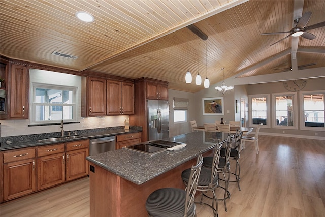 kitchen with a kitchen island, appliances with stainless steel finishes, decorative light fixtures, sink, and light hardwood / wood-style floors