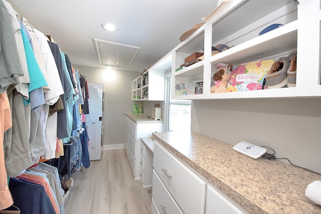 walk in closet with attic access and light wood-type flooring