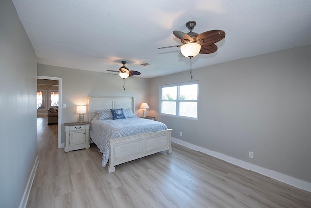 bedroom featuring multiple windows, light hardwood / wood-style floors, and ceiling fan