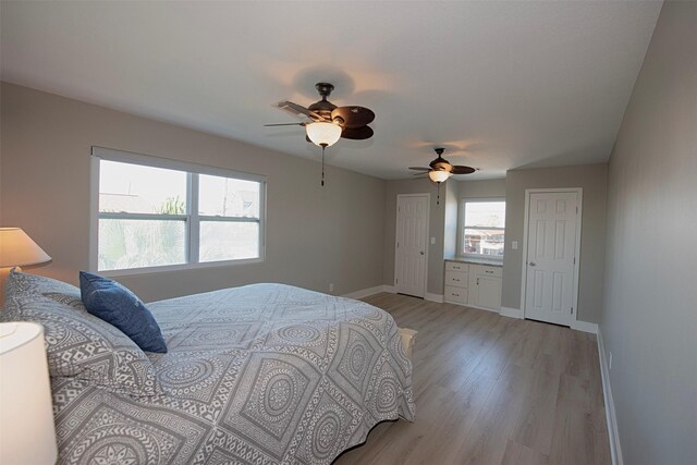 bedroom featuring ceiling fan, multiple closets, light wood-type flooring, and baseboards