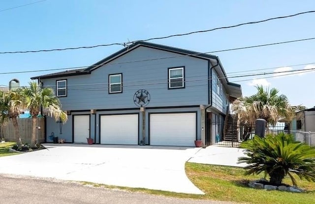 view of front of house with stairs, driveway, fence, and a garage