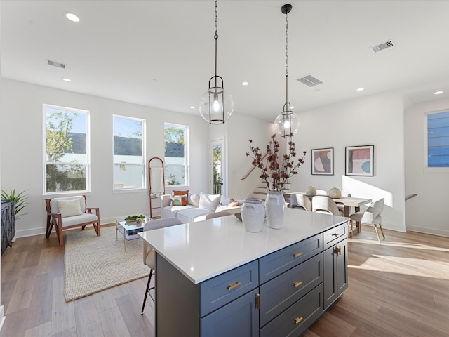 kitchen with a breakfast bar, hanging light fixtures, a center island, and light wood-type flooring