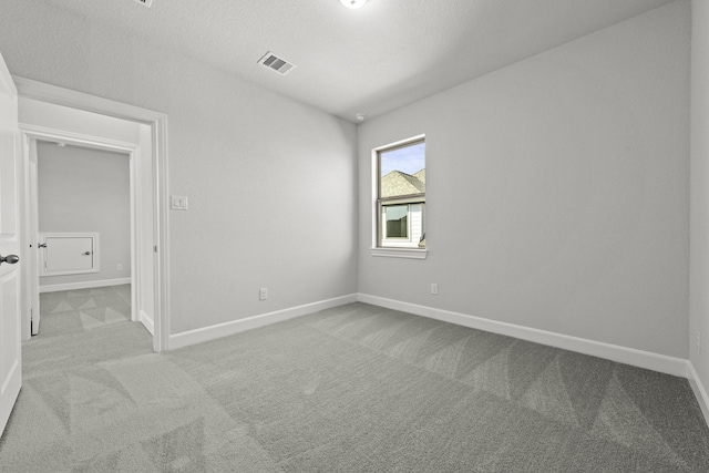 unfurnished room featuring visible vents, carpet floors, a textured ceiling, and baseboards