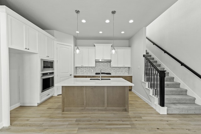 kitchen featuring oven, built in microwave, light wood-style floors, and tasteful backsplash