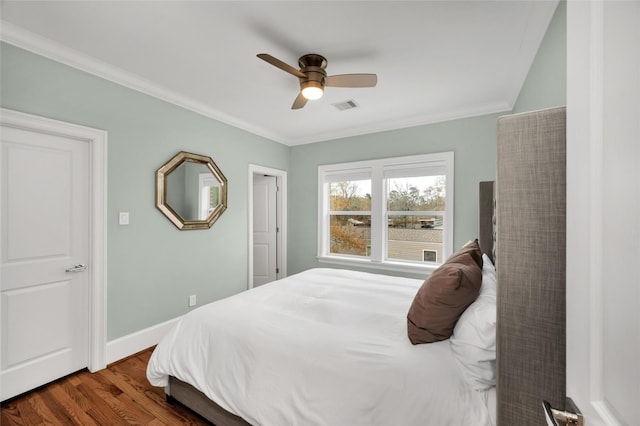 bedroom featuring crown molding, dark wood-type flooring, and ceiling fan